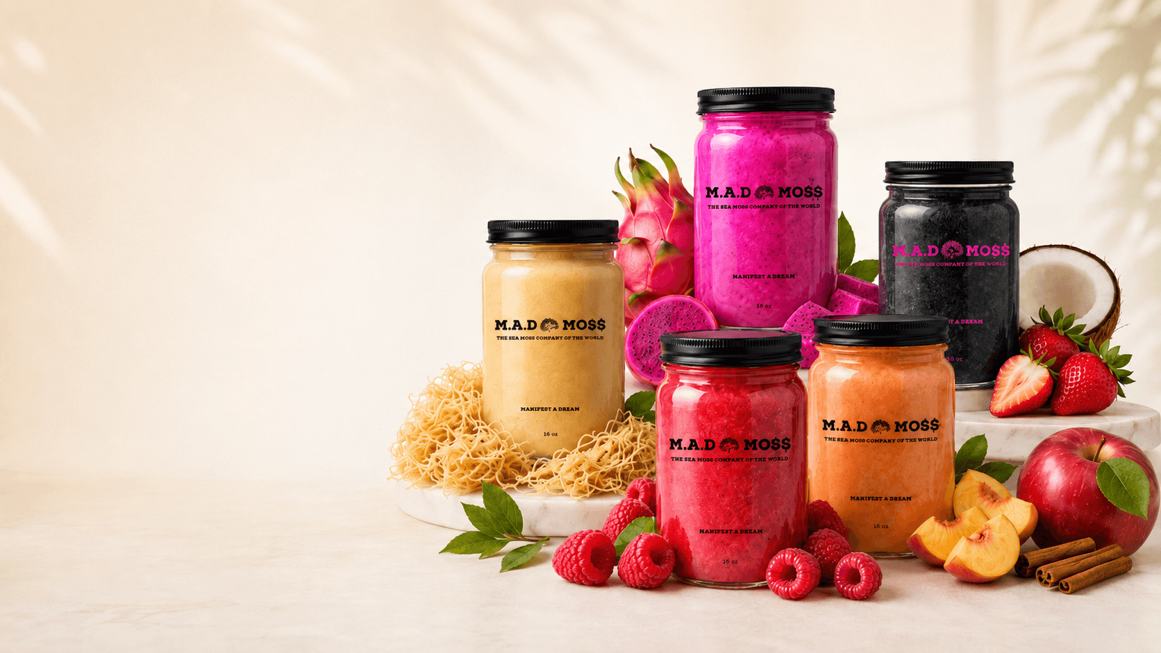 A lineup of branded M.A.D MO$$ sea moss gel jars in colorful flavors with fresh fruit