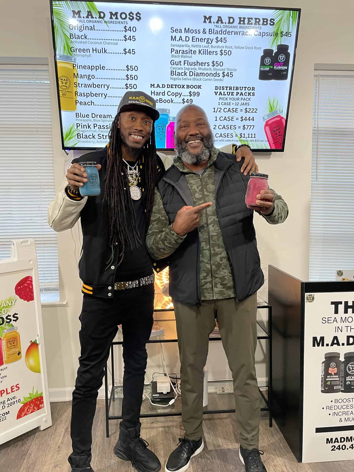 The founder with a customer in front of the M.A.D MO$$ menu