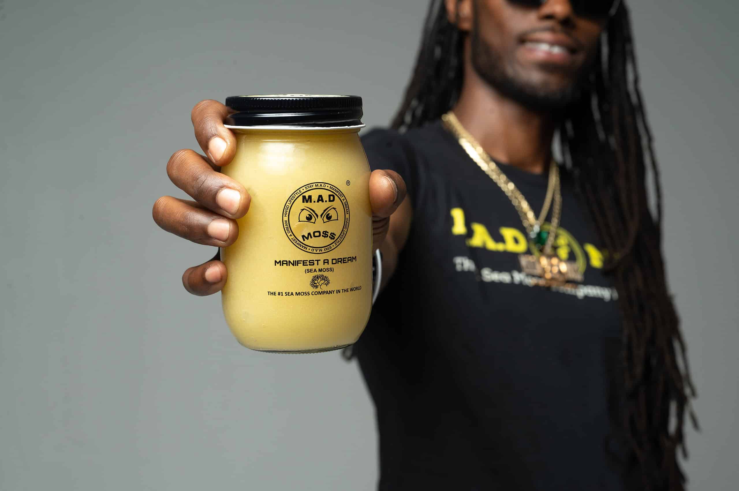 The founder of M.A.D MO$$ holding a jar of Original sea moss gel